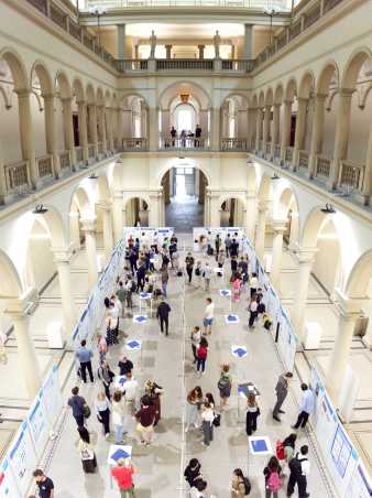 Poster exhibition in the main hall seen from above. Many people looking at posters.