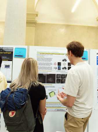 Two people seen from behind studying a scientific poster