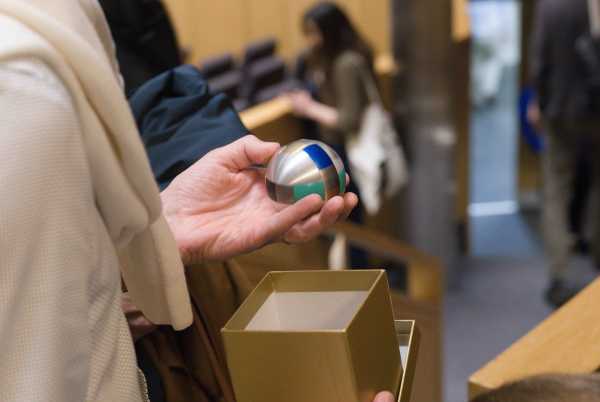 A hand holding a ball above a golden box