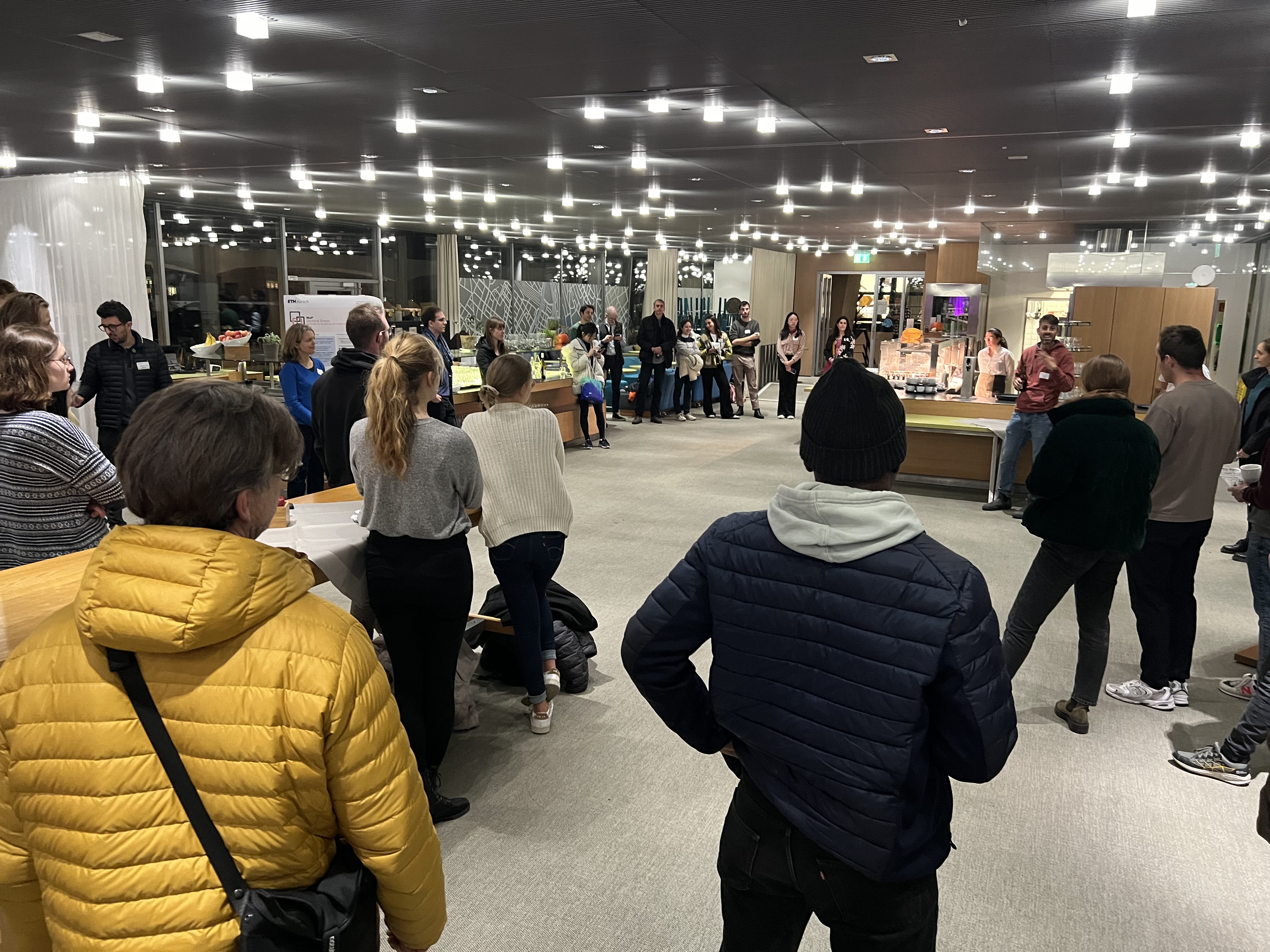 People scattered around the Dozentenfoyer, listening to Prof. Lucio Isa holding a welcome address.