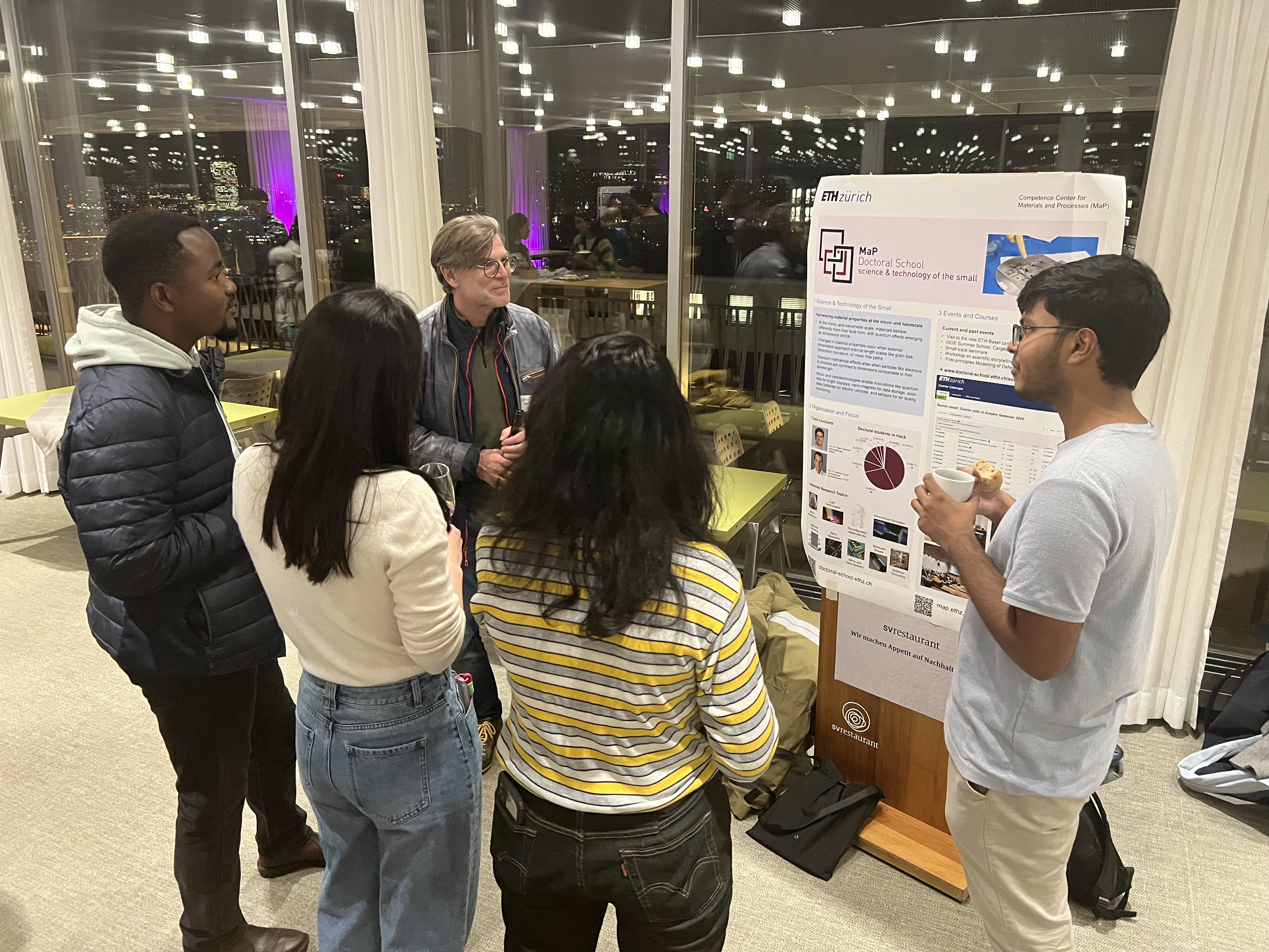 Prof. Ralph Spolenak and a group of 4 students discussing in front of one of the posters.