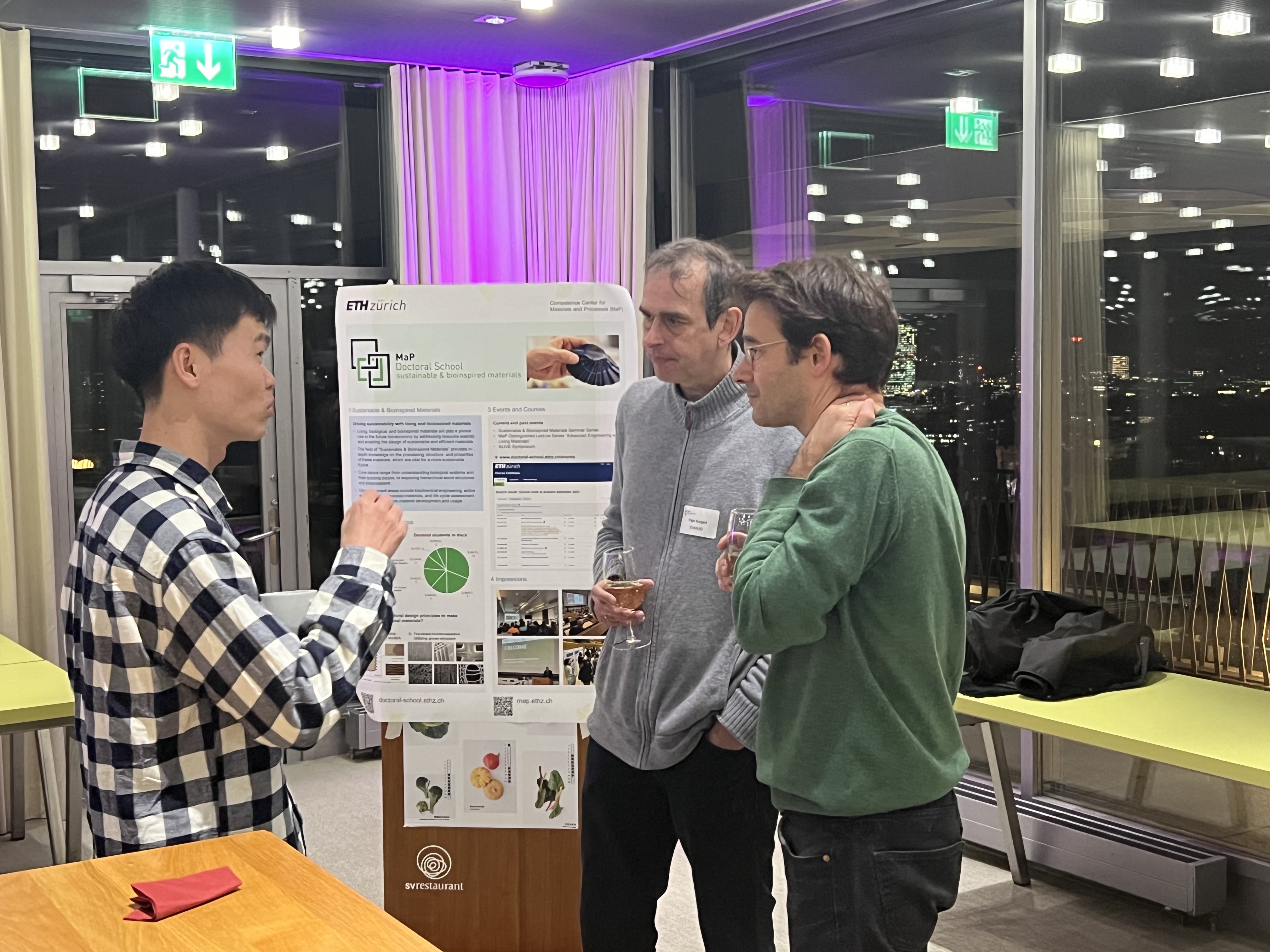Prof. Ingo Burgert and two students discussing in front of one of the posters.