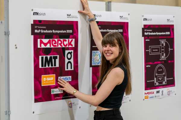 Mélanie Rouèche from the organising committee hanging up a sponsor poster