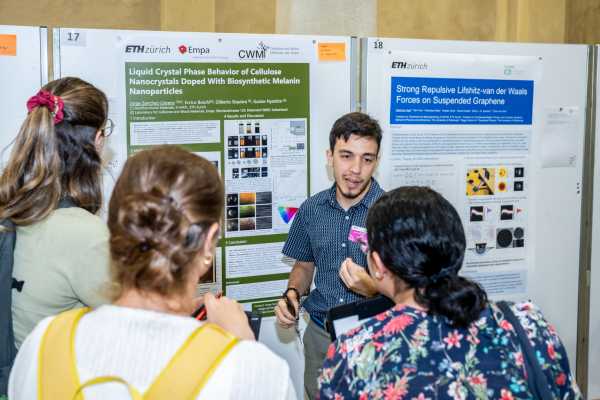 4 people standing in front of a scientific poster, one of which seemingly explaining something