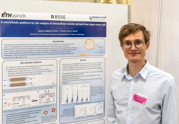 one guy chest up in front of his scientific poster