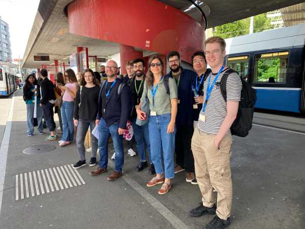 a group of people with workshop lanyards waiting at a bus stop