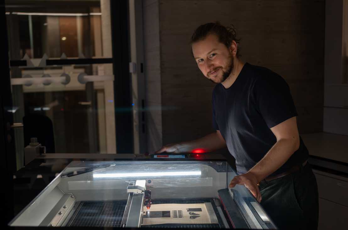 Christopher at the CO2 laser engraver, graphitizing wood to make it electrically conductive.