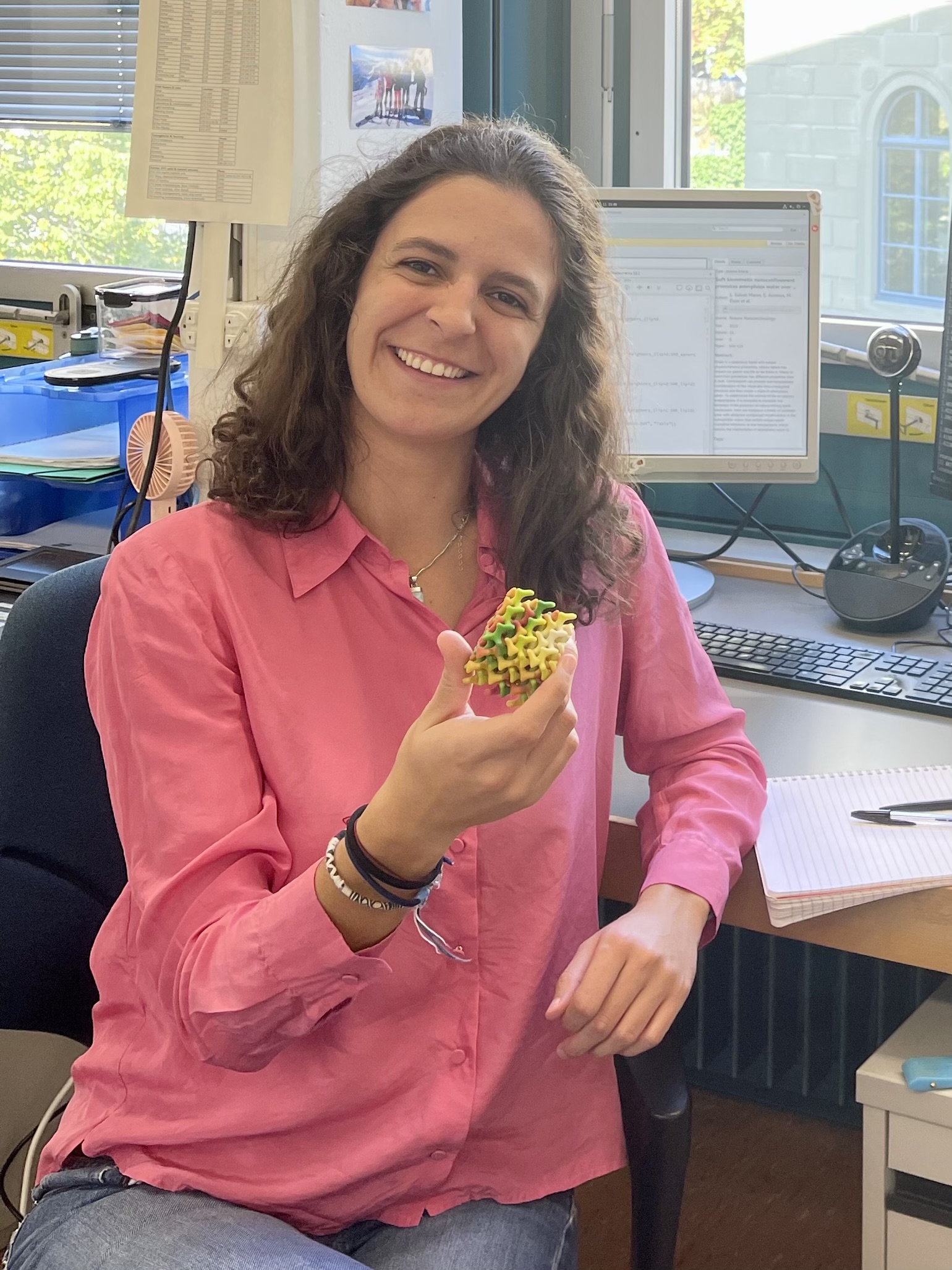 Portrait of a young woman sitting at a desk, holding a model in her hand